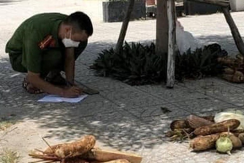 Chien si cong an chia rau cu cho nguoi dan giua trua nang hinh anh