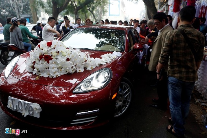 Chiếc xe Porsche màu đỏ được sử dụng làm xe rước dâu. Tuấn Hưng đề nghị trang trí xe hoa bằng lan trắng và hồng đỏ. Biển xe được thay bằng tấm bảng dễ thương với chữ 