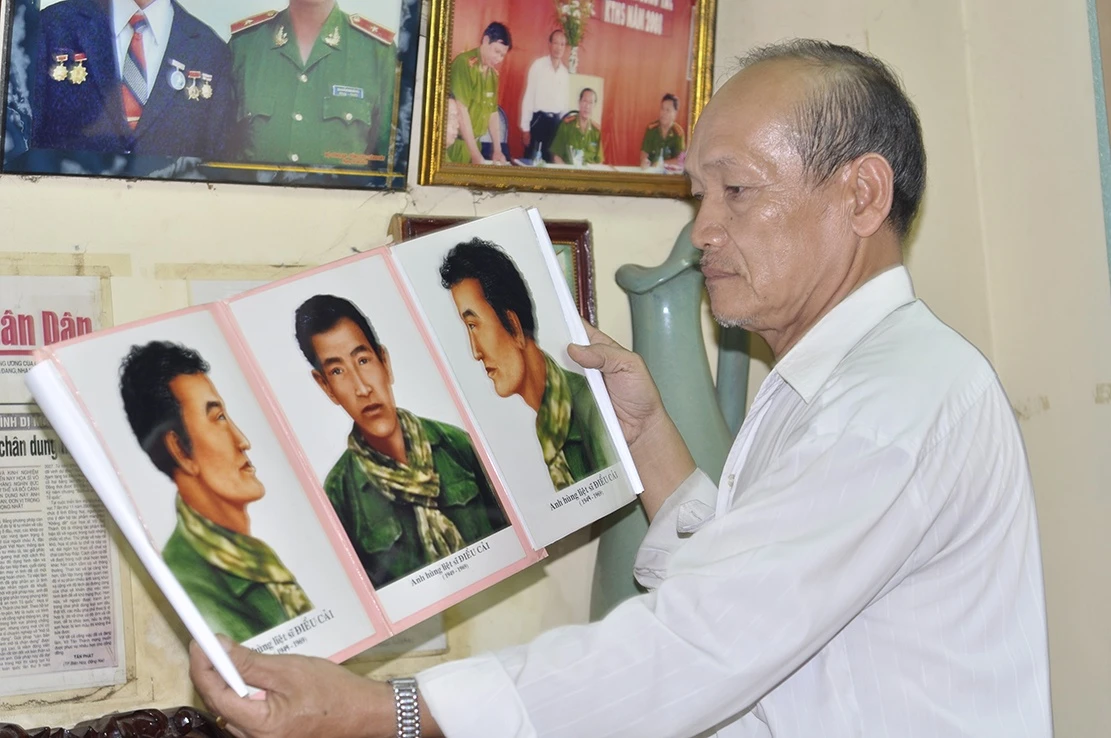 Họa sĩ Thành bên bức chân dung anh hùng, liệt sĩ Điểu Cải. Ảnh: Ngọc An 