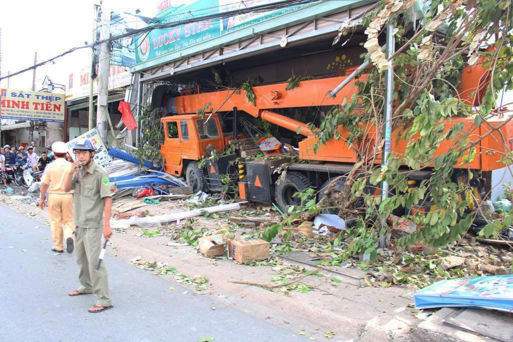 Xe cau cuon 3 nguoi vao gam roi dam vao cua hang ben duong hinh anh