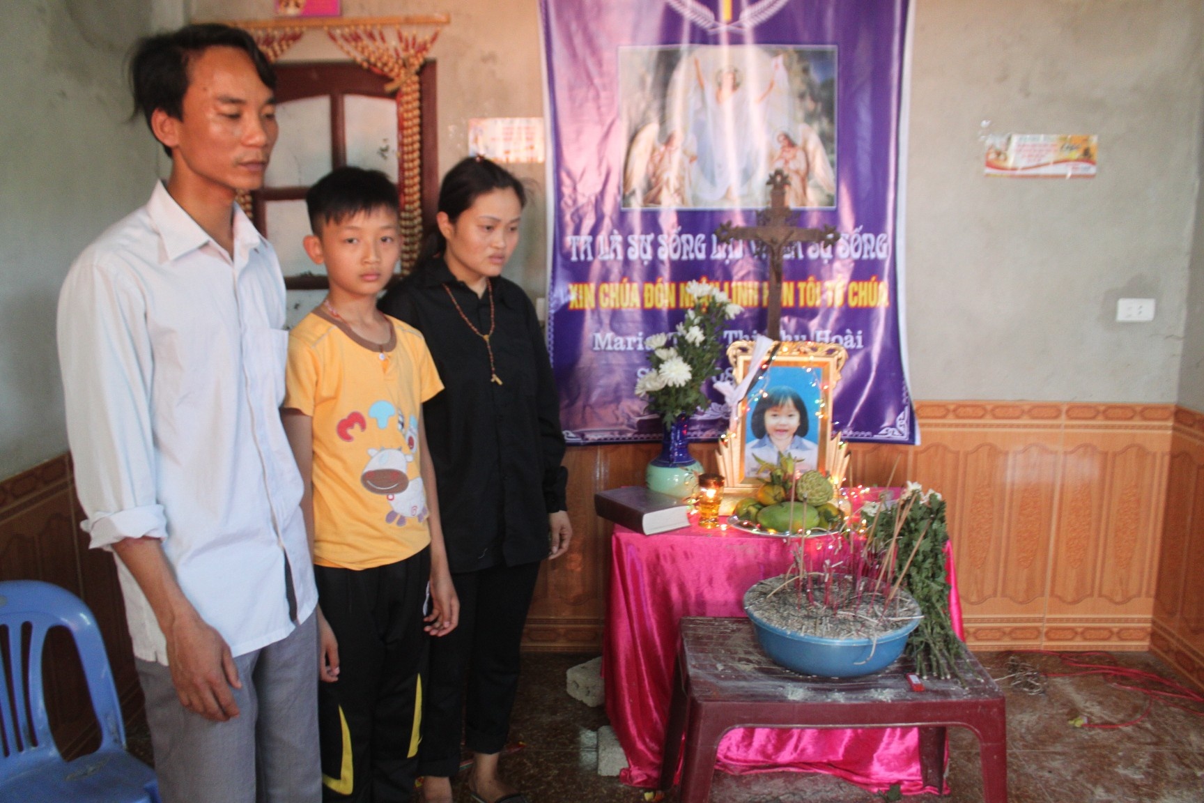 Vợ chồng anh Minh, chị Mai và đứa con trai đầu bên di ảnh bé Hoài.