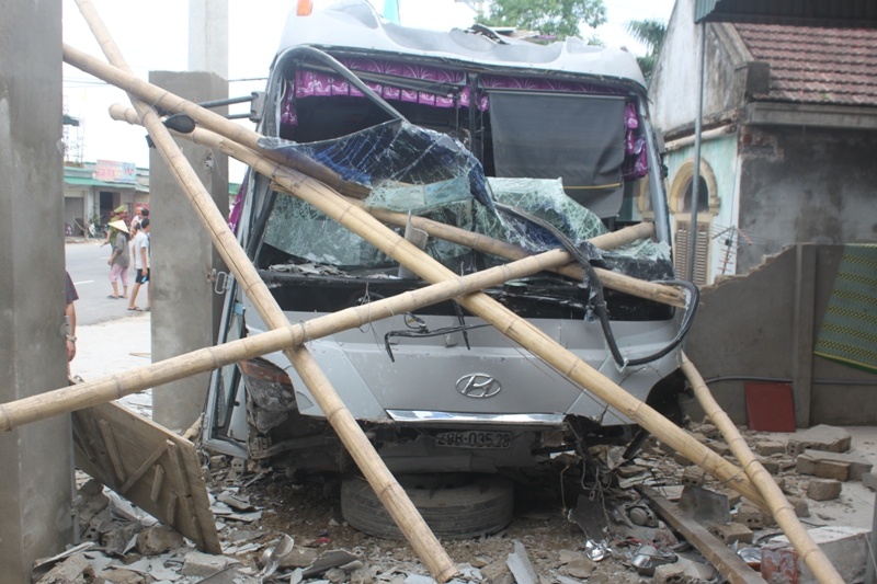 Chiếc xe khách bị hư hỏng nặng sau khi đâm vào nhà dân. Kính phía trước bị nát bét hoàn toàn.