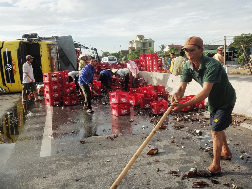 Xe cho hang tram thung bia bi lat, dan ua ra giup thu gom hinh anh