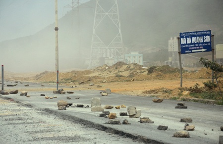 Lập hàng rào, cắt cử bảo vệ cũng không ngăn được đoàn xe quá tải này, buộc nhà thầu phải xếp đất đá bảo vệ phần đường vừa được thảm nhựa