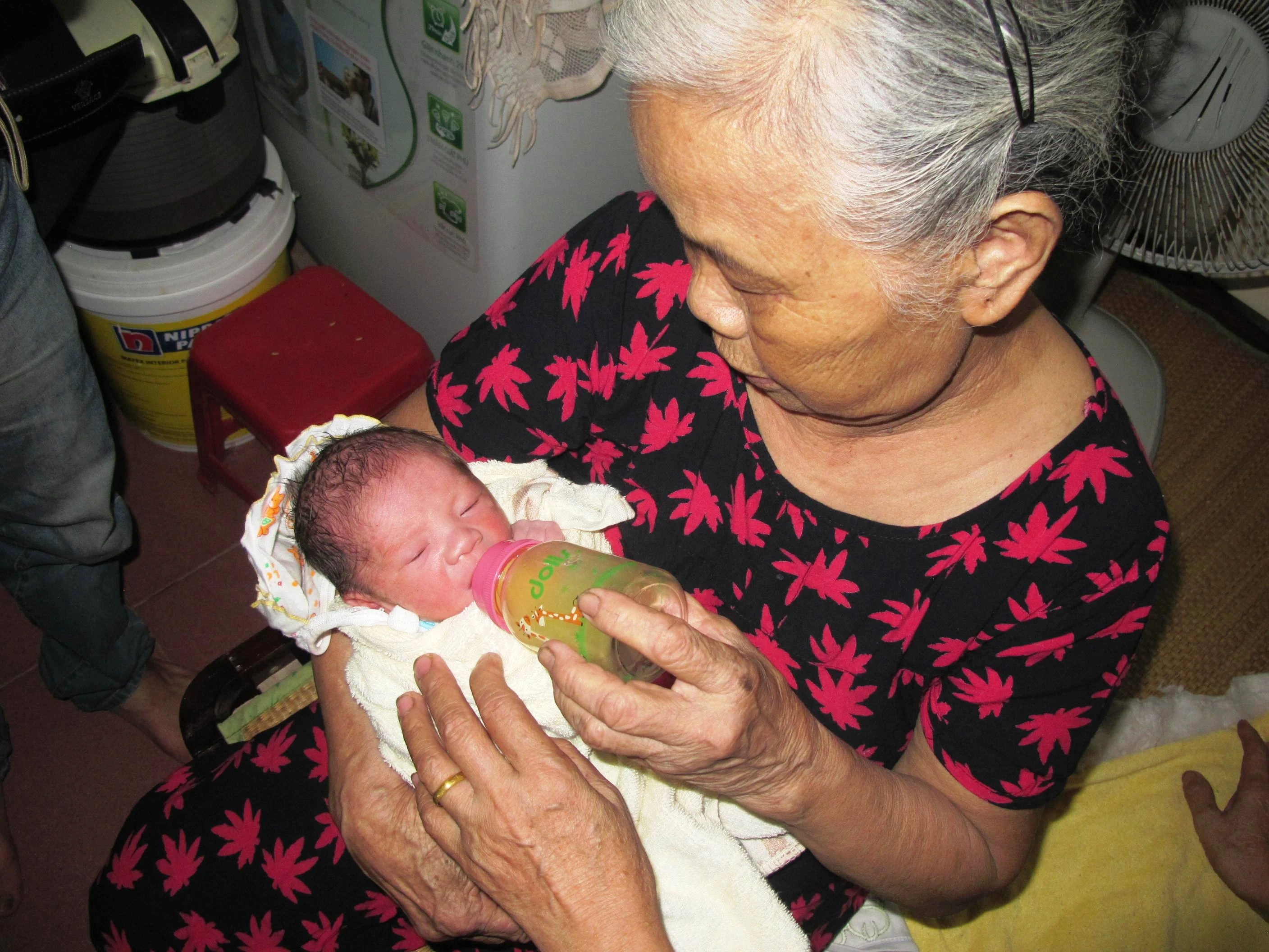 Cụ Phương đang cho cháu bé bú sữa.