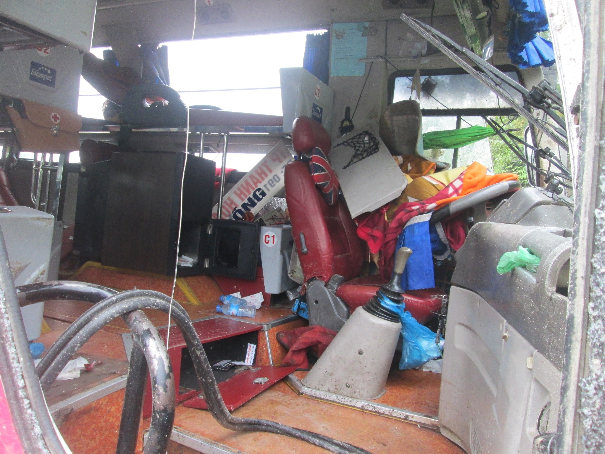 Bên trong xe bị lật đồ đạc lộn xôn, một số hàng hóa dưới gầm xe rơi ra ngoài, văng tung tóe khắp nơi. 