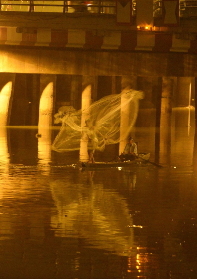 Người đàn ông quăng lưới trên kênh Nhiêu Lộc - Thị Nghè, đoạn dưới chân cầu Điện Biên Phủ để bắt cá.