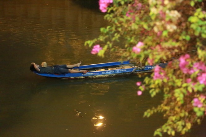 Một người ngủ ngay trên ghe chờ nước rút để chích điện bắt cá.