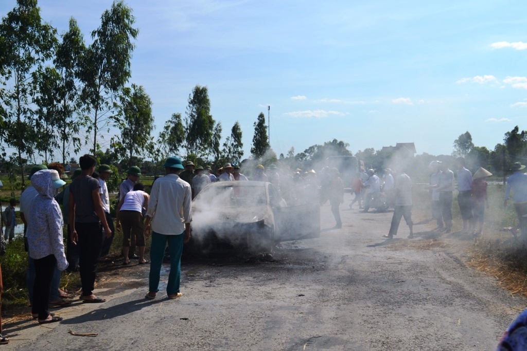 Chủ xe cùng nhiều người dân hợp sức chữa cháy cho chiếc xe. Ảnh: T.Chung.