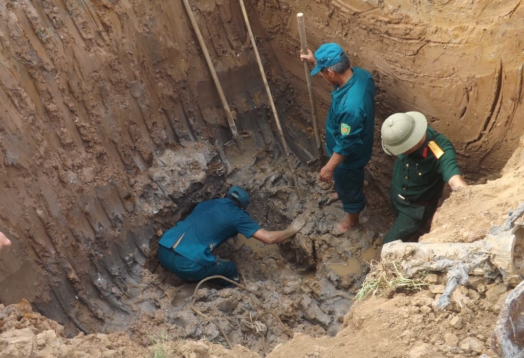 Các chiến sĩ cùng máy xúc đang đào đất để đưa quả lên lửa lên bờ. Ảnh: Lê Hùng.