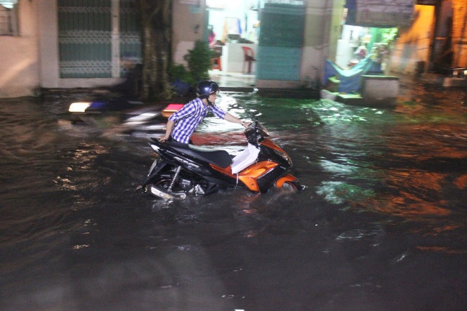 Một thanh niên đẩy xe chết máy giữa mênh mông biển nước trên đường An Dương Vương, quận 6.