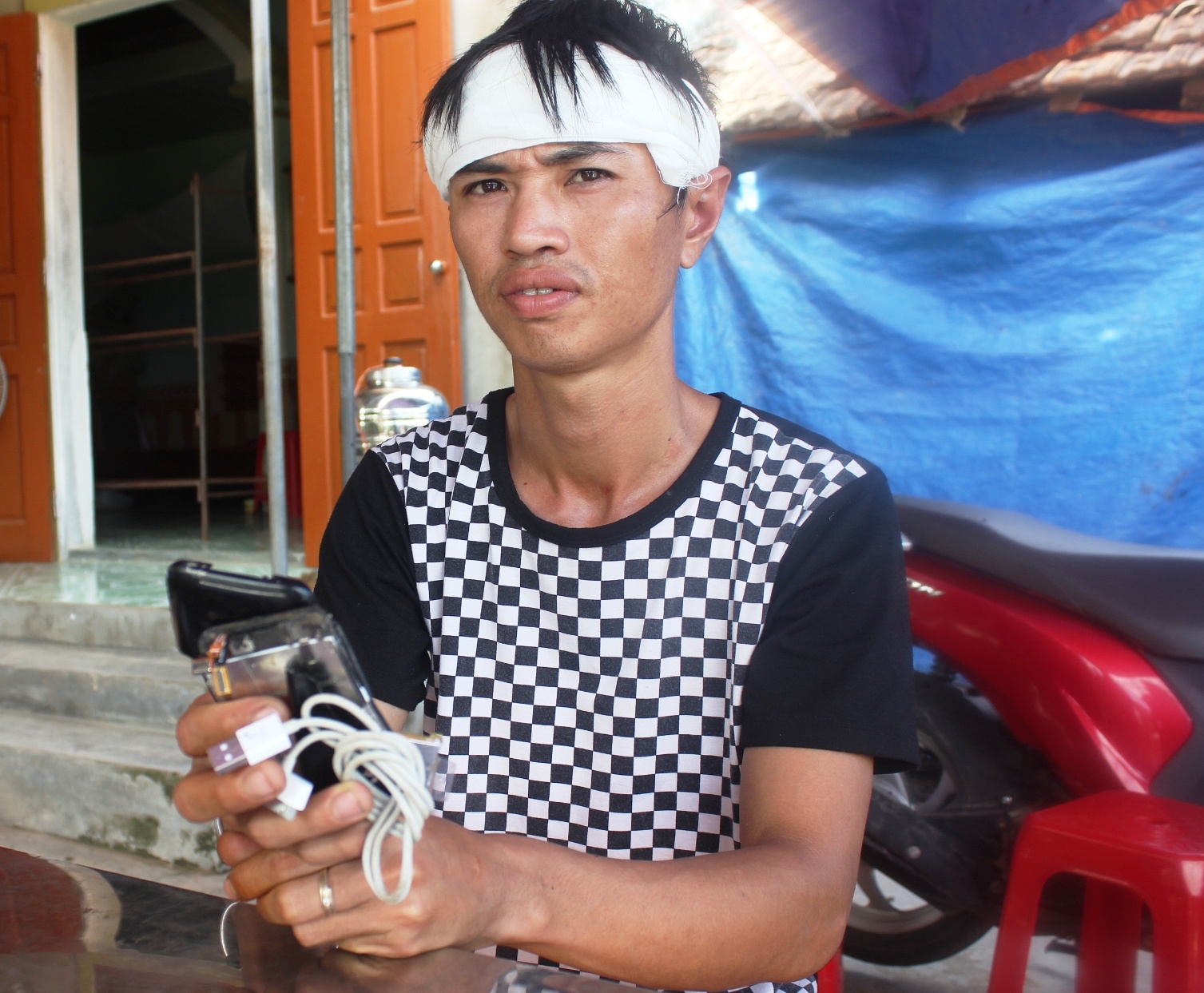 Anh Quân cầm trên tay chiếc ịhone 3 bị vỡ vụn. ẢNh: Phạm Hòa.