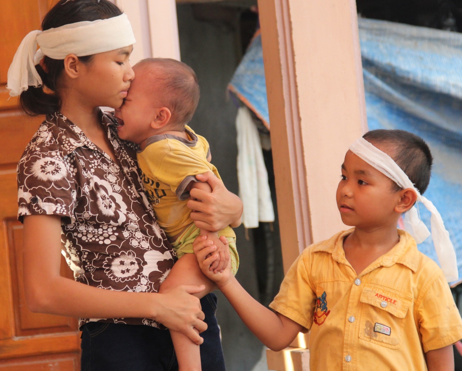 Ngọc bế đứa em út khi cháu liên tục đòi bú sữa mẹ. Bên cạnh Hiệp vẫn hồn nhiên nhìn chị và em. Ảnh: Khánh Ngọc.