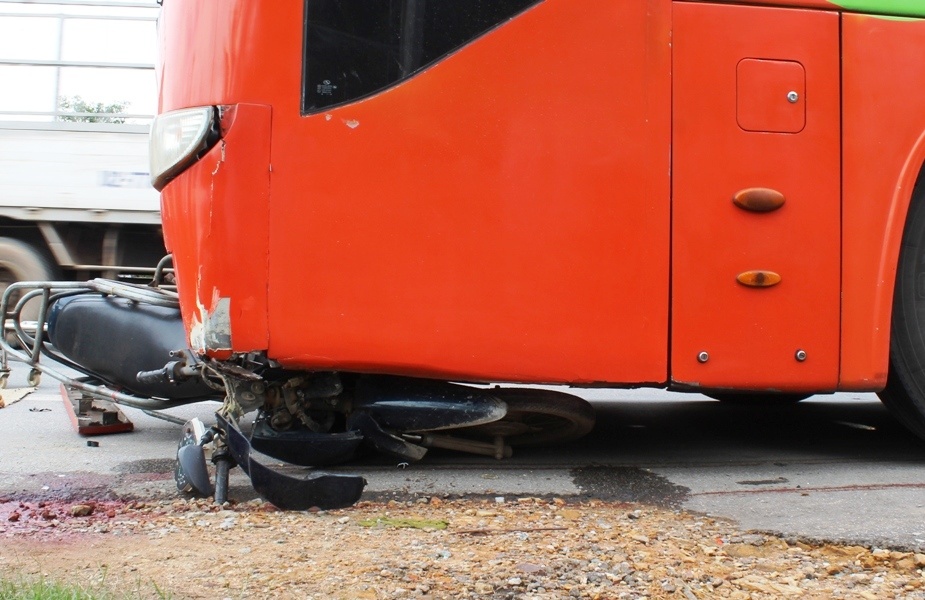 Chiếc xe máy nằm dính chặt trước gầm ôtô khách. Ảnh: Phạm Hòa.