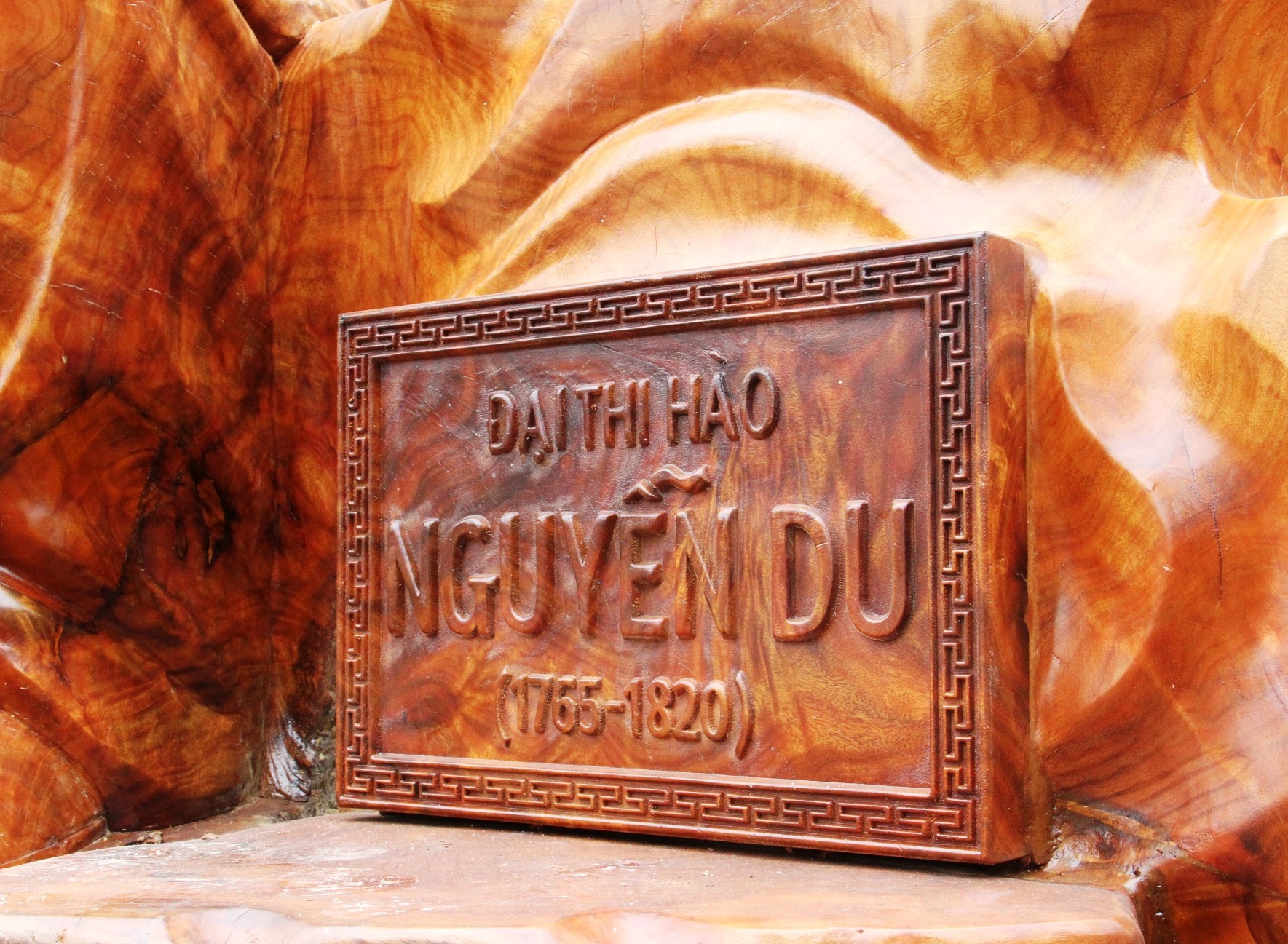 Bên cạnh bức tượng là tấm biển khắc tên và năm sinh năm mất của Đại thi hào Nguyễn Du.