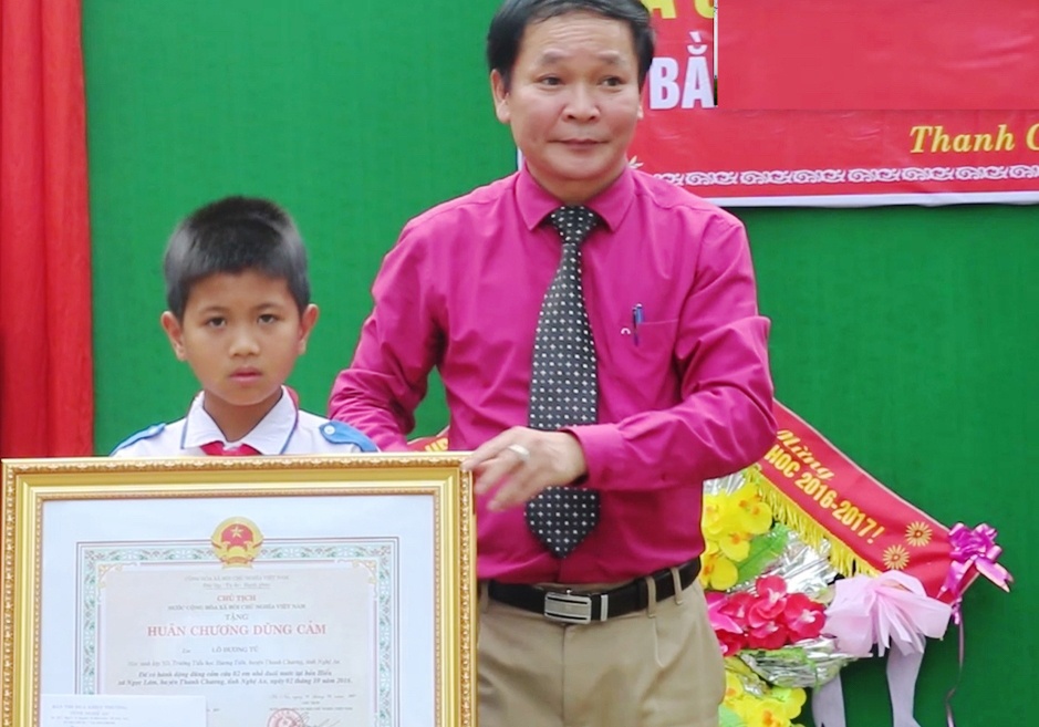 Trao Huan chuong dung cam cho nam sinh lop 5 cuu hai em duoi nuoc hinh anh