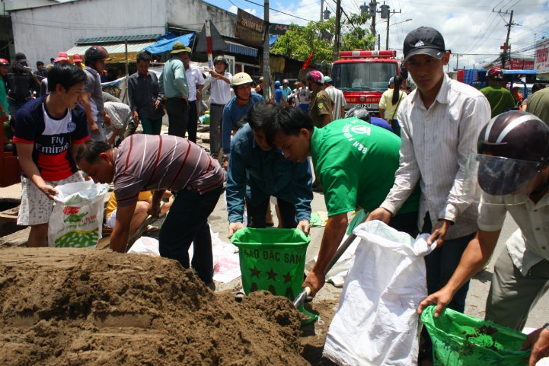 Người dân tích cực cho cát vào bao tải để chặn cống nước. 