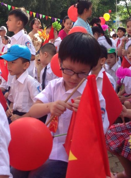 Quốc Anh - thành viên nhóm Biển Xanh - chụp lại khoảnh khắc con trai đang loay hoay gắn lại lá cờ trong ngày khai trường. 