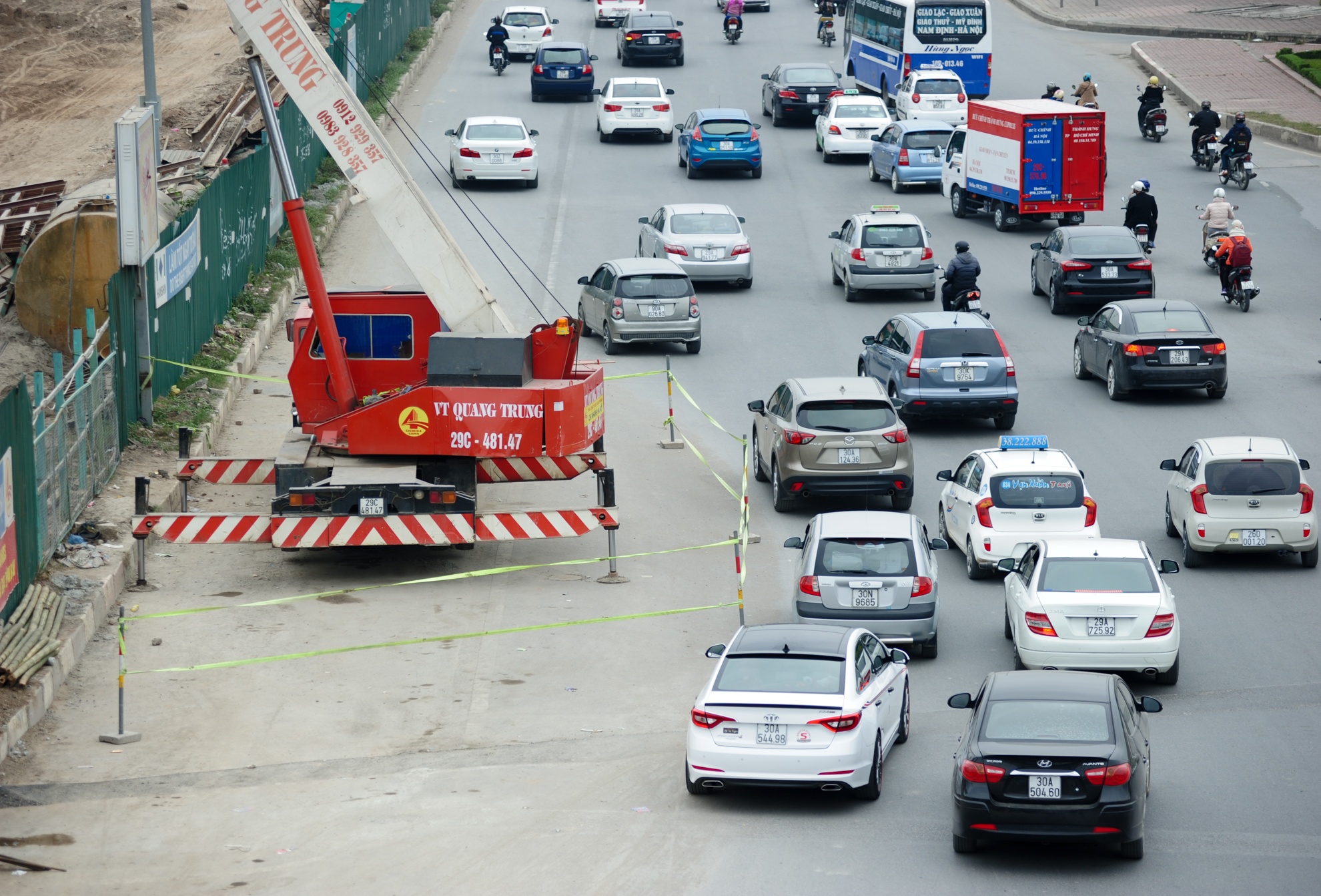 Phía đầu đường Đại lộ Thăng Long, một chiếc cần cẩu làm việc trên lòng đường khiến đường khu vực này bị thu hẹp lại. Các phương tiện đều phải lượn vòng để né tránh.
