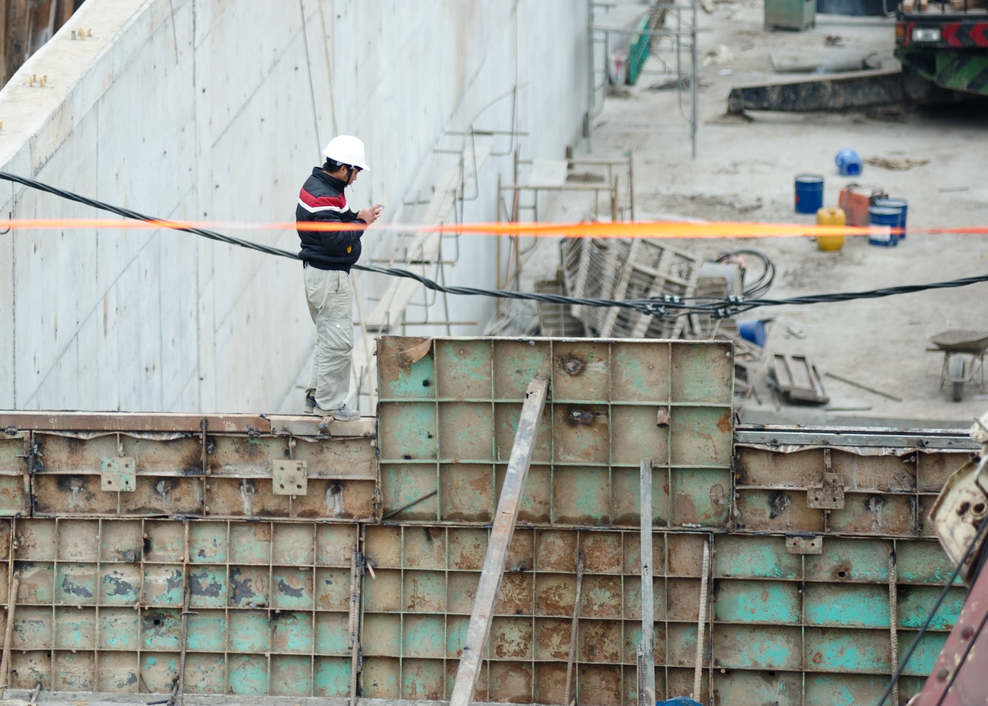 Trong công trường, nhiều công nhân đứng ở trên thành cao mà không mang dây bảo hộ. Cá biệt có người còn đứng trên vách công trường cheo leo để sử dụng điện thoại di động.