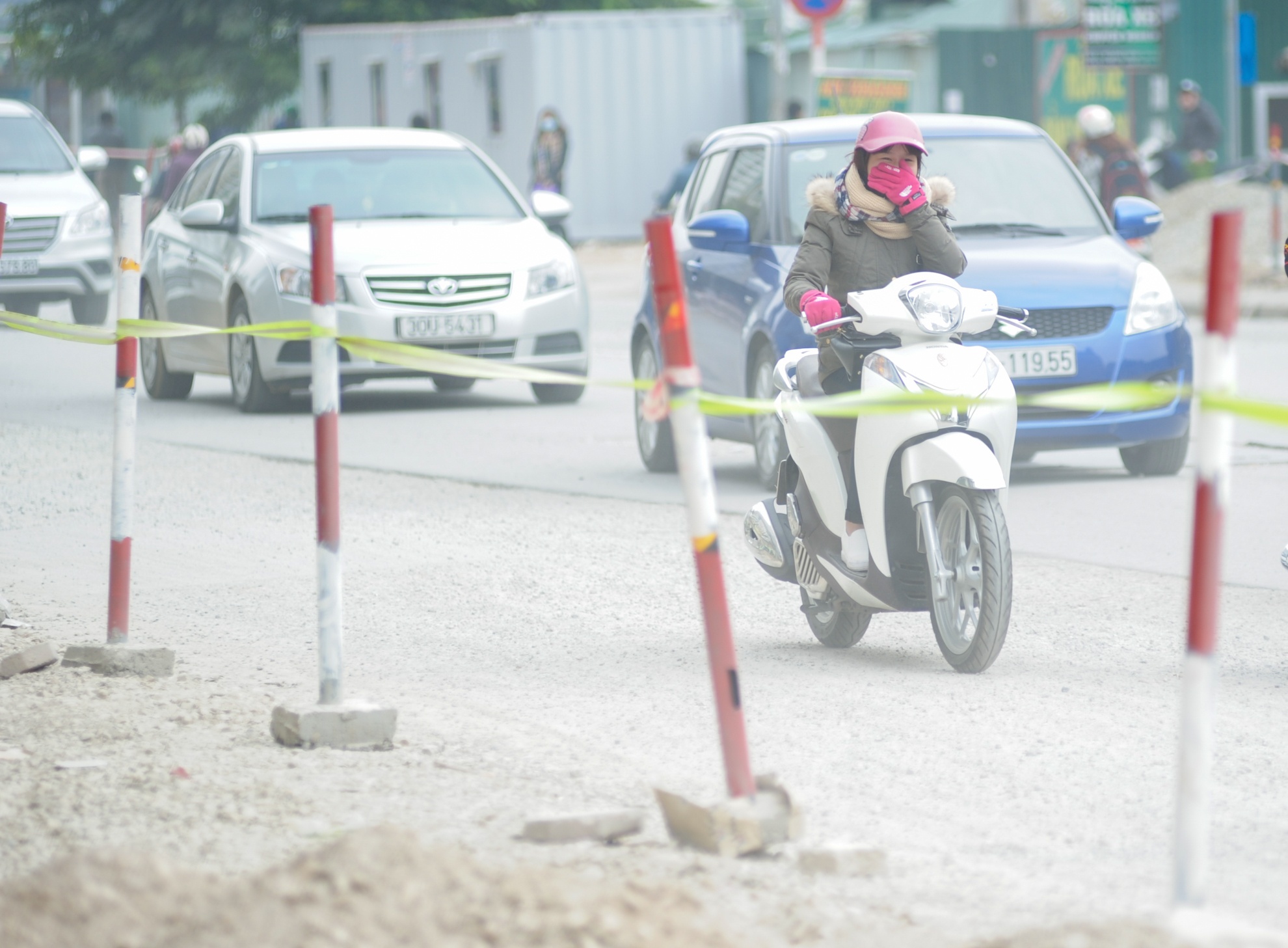 Trên đường Hoàng Minh Giám, đoạn giao với Trần Duy Hưng, người đi xe máy phải bịt mũi hoặc đeo vội vàng khẩu trang khi đất cát bị cuốn lên từ con đường đang làm dở.