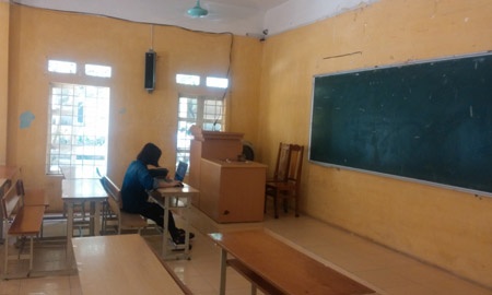 Một SV tranh thủ phòng học không có lớp ngồi ôn bài dưới quạt mát.