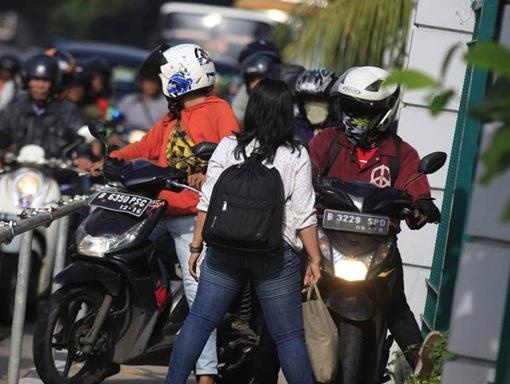 Nguoi phu nu dang tay chan xe may leo len via he hinh anh