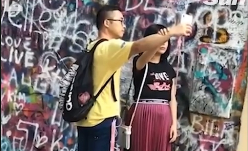 Co gai gay cuoi khi dung ban trai lam cong cu chup anh hinh anh