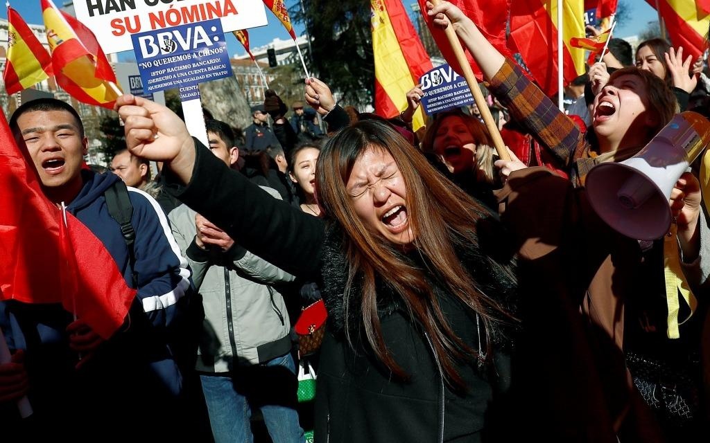 Nguoi TQ bieu tinh phan doi ngan hang Tay Ban Nha phan biet chung toc hinh anh