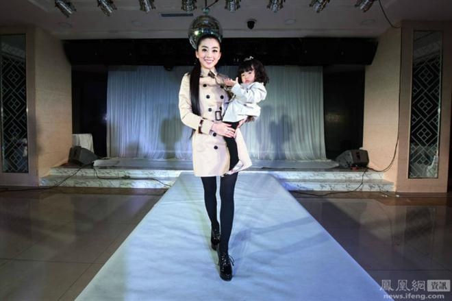 Bà mẹ 9x xinh đẹp bế con gái trên sàn catwalk.