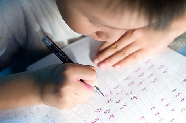 Ngồi sai tư thế cúi gằm xuống bàn là tư thế dễ phạm phải của trẻ học chữ sớm. Ảnh tư liệu