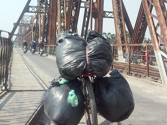 Chang trai di xe dap gom tui nilon tren cau Long Bien hinh anh