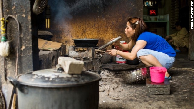 Một người phụ nữ ở quán thổi bếp để giữ lửa cháy. 