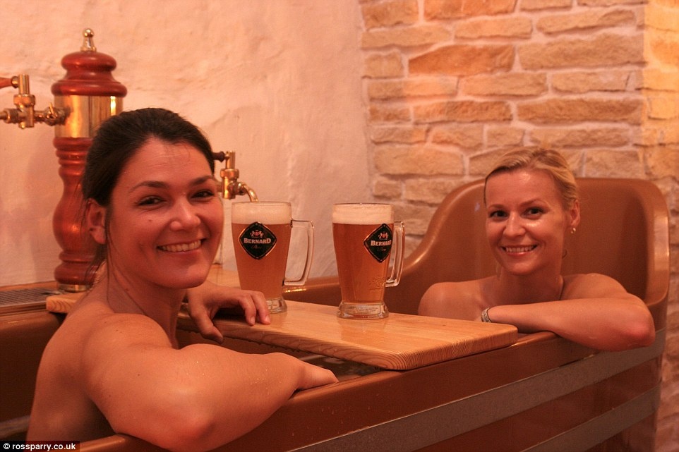 Hai du khách nữ đang ngâm mình và uống bia ở Beer Spa tại Prague, nơi du khách có thể thỏa mãn đam mê với bia từ ngoài vào trong. Ảnh: Dailymail.