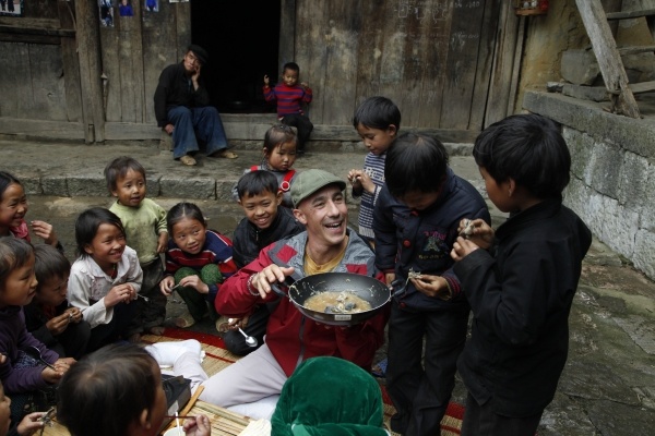 Robert cùng thưởng thức món ăn với trẻ em Hà Giang. Ảnh: ĐIỀN QUÂN Media & Entertainment