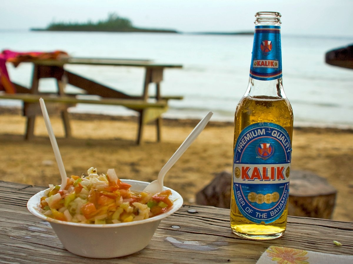Thưởng thức món salad Bahamia cầu kỳ và một chai bia Kalik lạnh trên bờ biển Bahamas