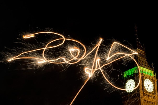 Một người dân London tạo hình với pháo hoa cầm tay đón chào năm mới dưới chân đồng hồ Bigben, London, Anh.