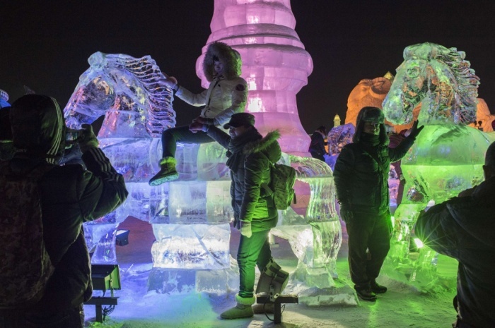 Các du khách mặc áo ấm dày chụp ảnh cùng các tác phẩm. Ảnh: Fred Dufour/AFP/Getty Images