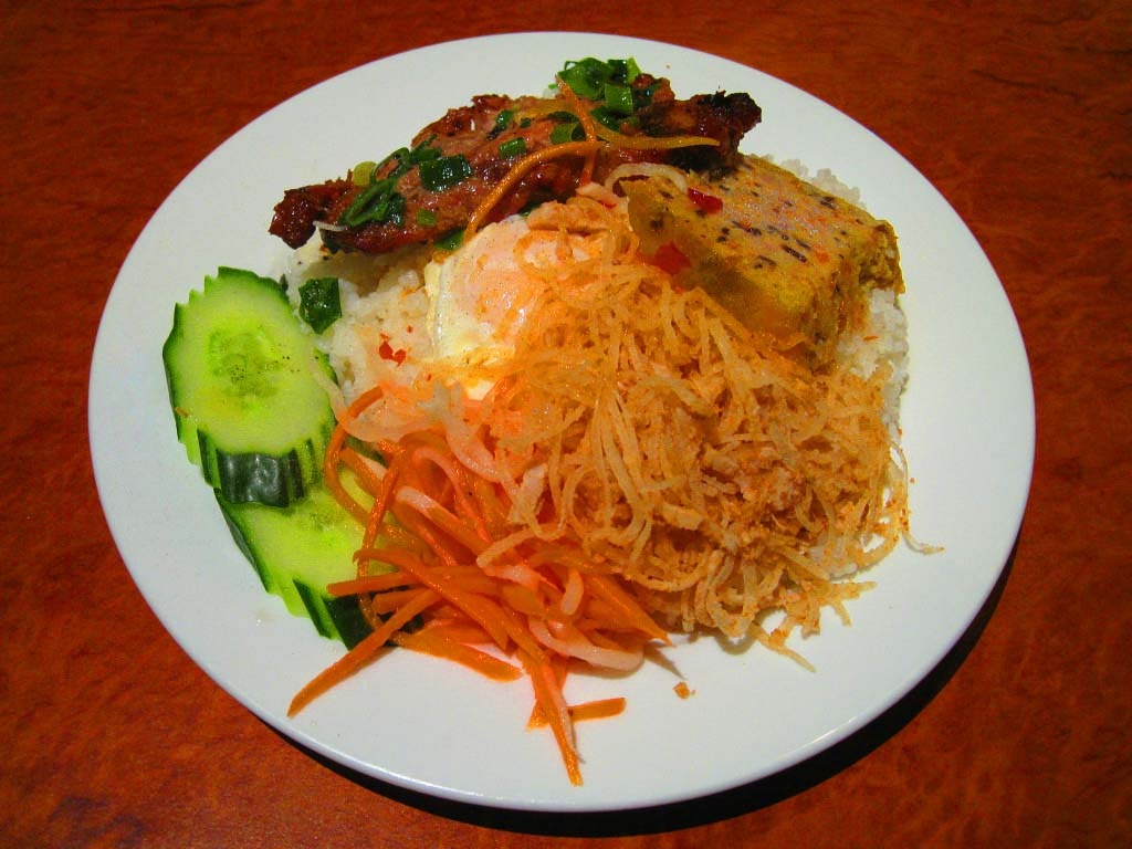 14. Cơm tấm: Đây là món đặc sản của Sài Gòn, được làm từ gạo vỡ, ăn kèm với sườn nướng, bì, chả, trứng và dưa chuột, rưới thêm nước mắm hoặc nước sườn nướng. Thực khách thường có thêm một bát nước dùng để ăn kèm cơm tấm.