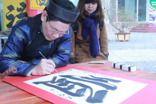 Hình ảnh ông đồ mặc áo dài, cặm cụi bên mực tàu giấy đỏ viết chữ khiến lòng người chộn rộn cảm xúc về một cái Tết xưa đơn sơ, ấm áp. Ảnh: Cao Thùy Liên