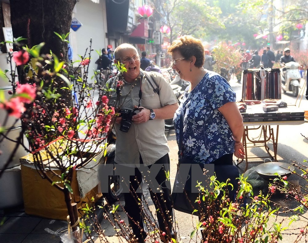 Du khách quốc tế thích thú với khung cảnh chợ hoa Tết Hàng Lược. (Ảnh: Minh Đức/TTXVN)