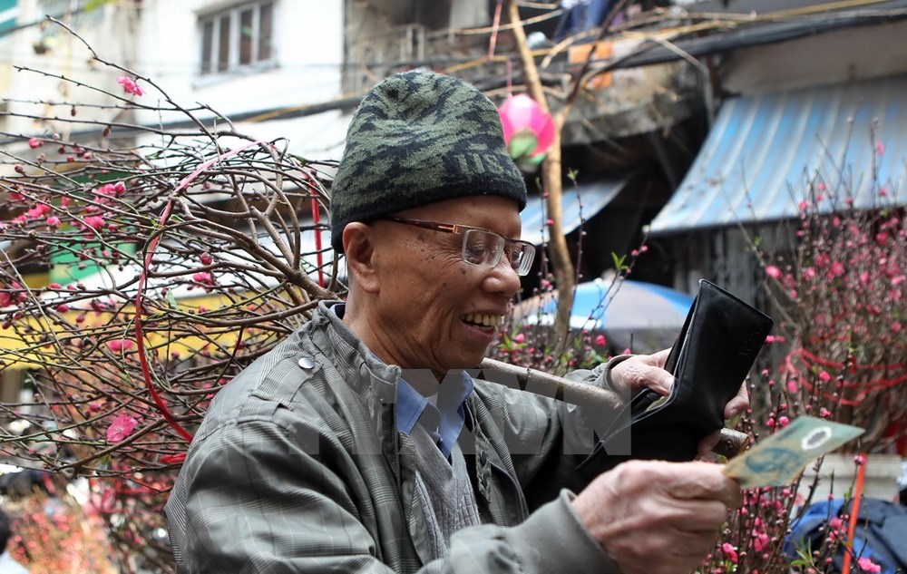 Vui mừng khi tìm mua được cành đào ưng ý. (Ảnh: Quốc Khánh/TTXVN)