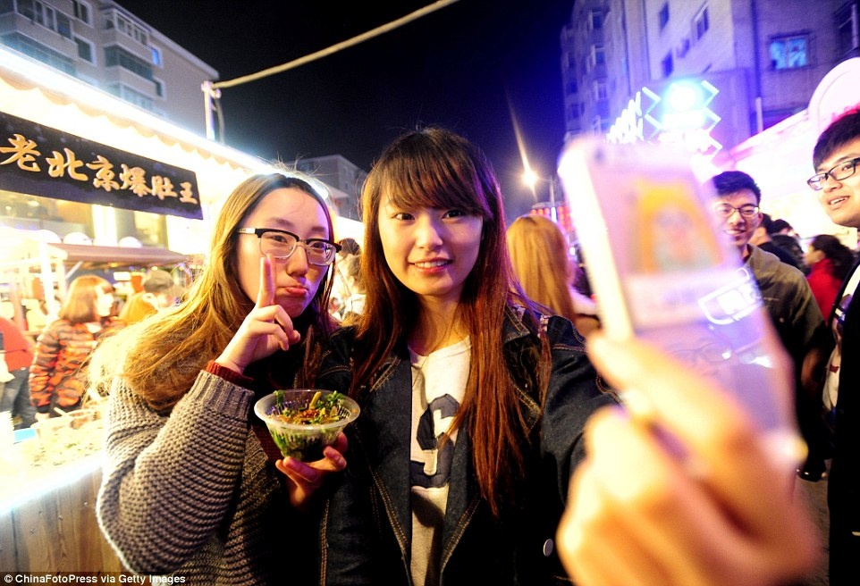 Đám đông bao quanh cả hai mặt các gian hàng được thắp sáng rực rỡ. Không khí nhộn nhịp, vui tươi, những người bán hàng ăn mặc đẹp và luôn miệng chào mời khách hàng.