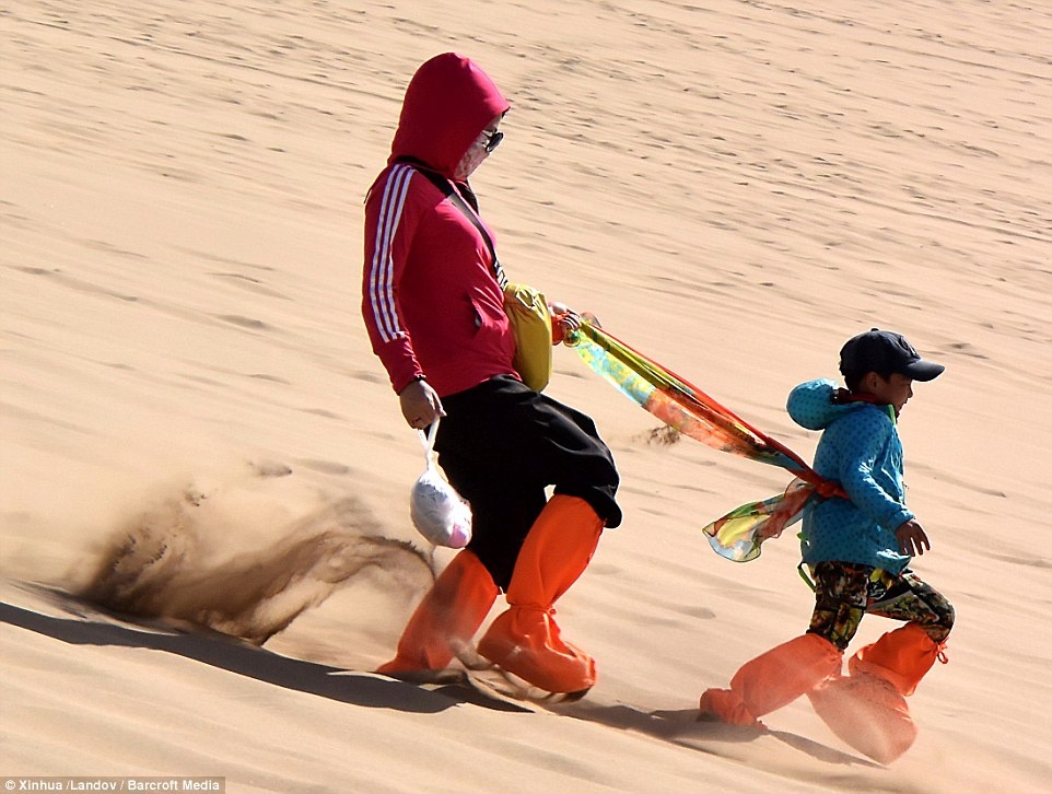 Du khách chơi đùa trên một đụn cát ở phần sa mạc Gobi thuộc tỉnh Cam Túc.