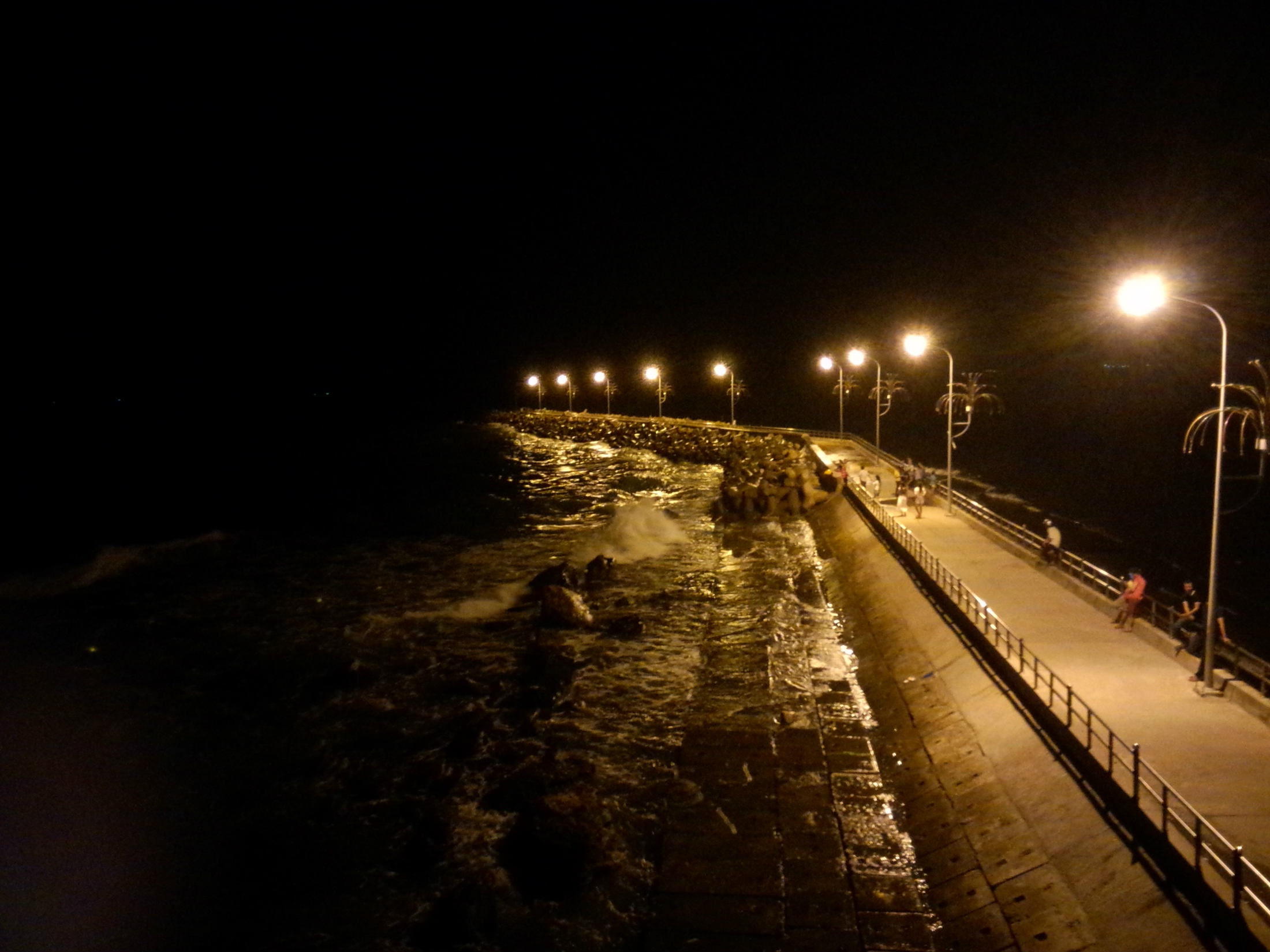 Cảnh cầu Dinh Cậu về đêm, ánh đèn huyền ảo soi sáng trên cầu, những con sóng vỗ tung bọt trắng xóa.