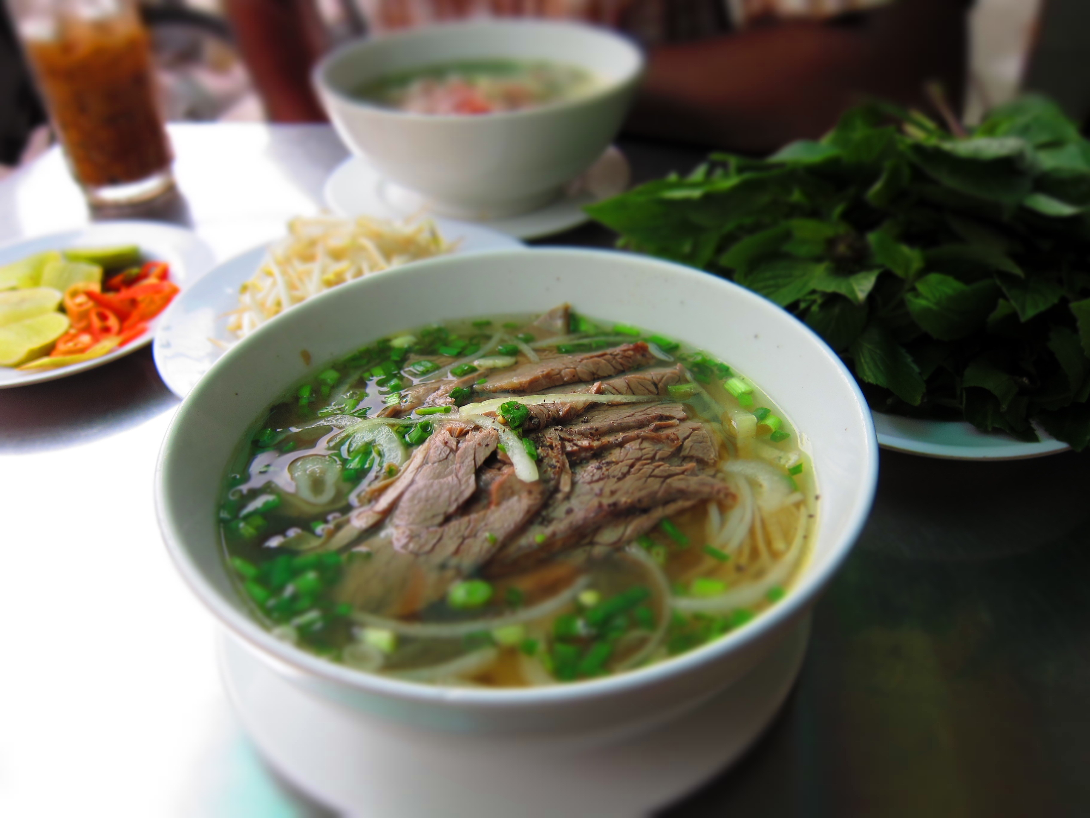 Phở, Việt Nam: Bánh phở được chan nước dùng ninh từ xương, thêm thịt gà hoặc thịt bò thái mỏng cùng rau thơm. Bạn có thể thưởng thức món ăn này ở mọi vùng của Việt Nam, với giá chỉ khoảng 1-<abbr class=