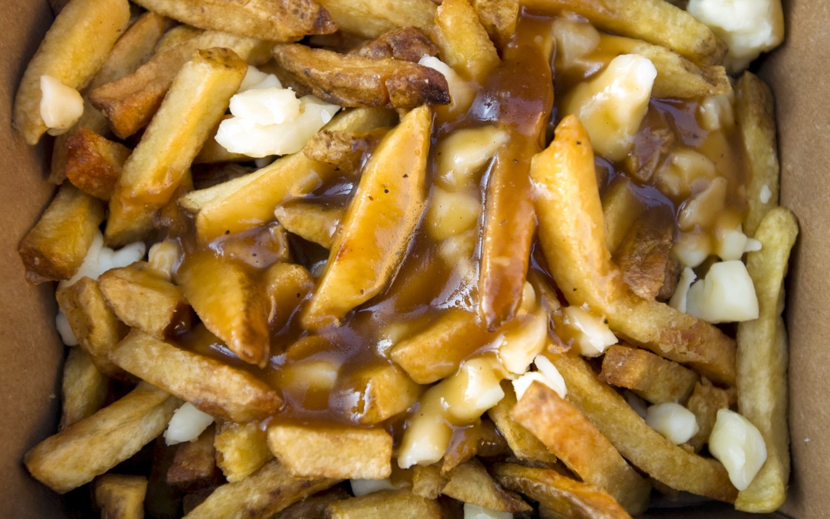 Poutine, Canada: Món ăn độc đáo này gồm khoai tây chiên rưới nước thịt và phô mai. Bạn có thể mua poutine trên hè phố với giá chưa tới <abbr class=