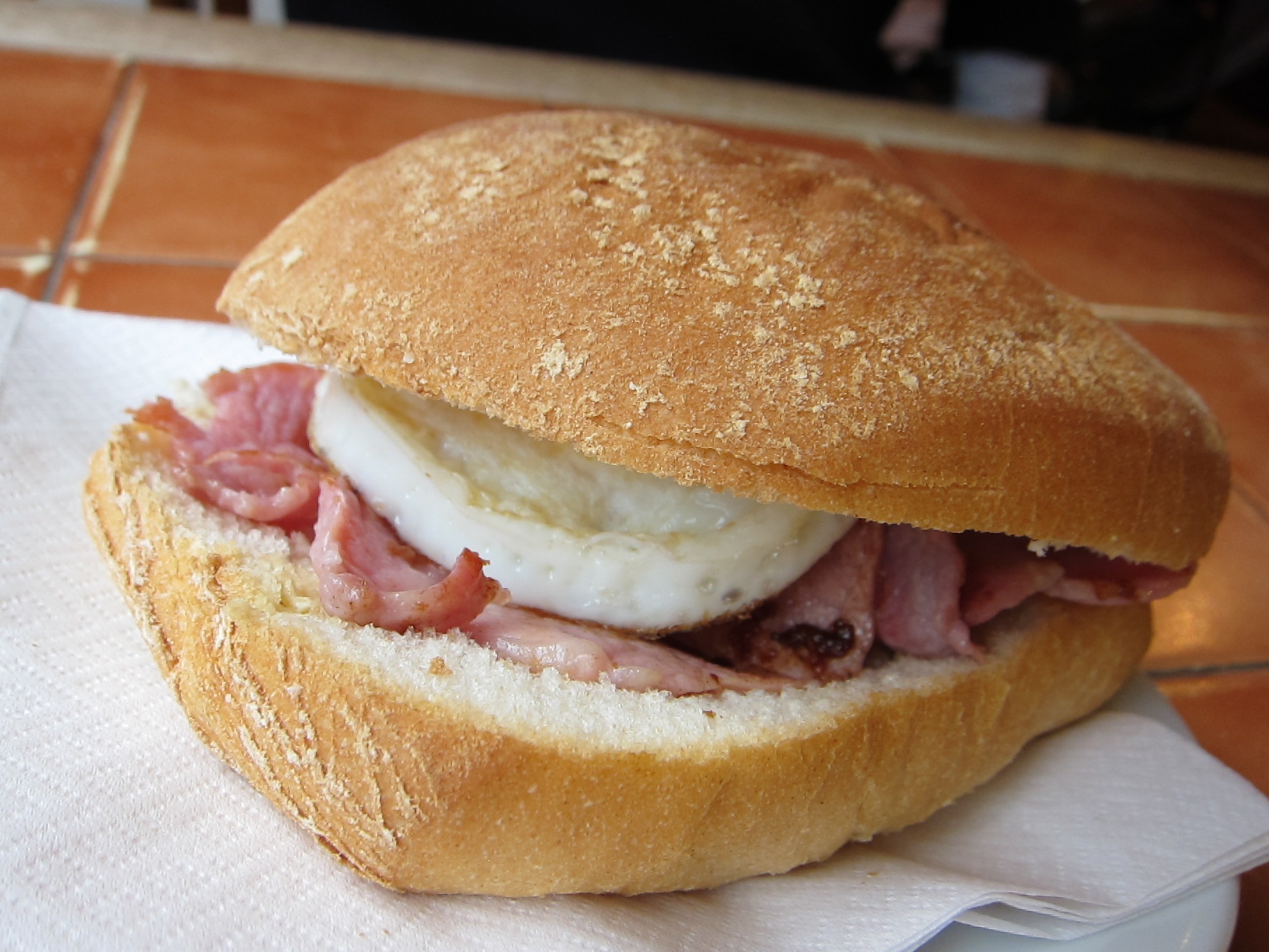 Bánh mì kẹp thịt hun khói, Scotland: Món bánh no bụng và ngon lành này được bày bán khắp Scotland, với giá khoảng <abbr class=