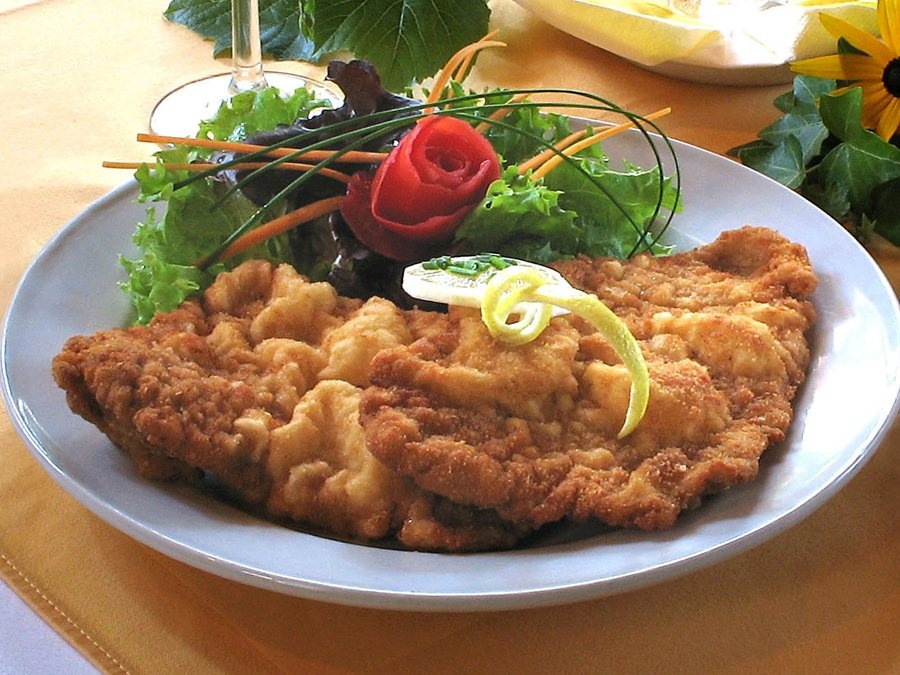 Wiener Schnitzel (Áo): Thịt bê được thái lát mỏng, tẩm vụn bánh mì và rán giòn, bày ra đĩa cùng chanh, rau mùi, khoai tây hoặc cơm.