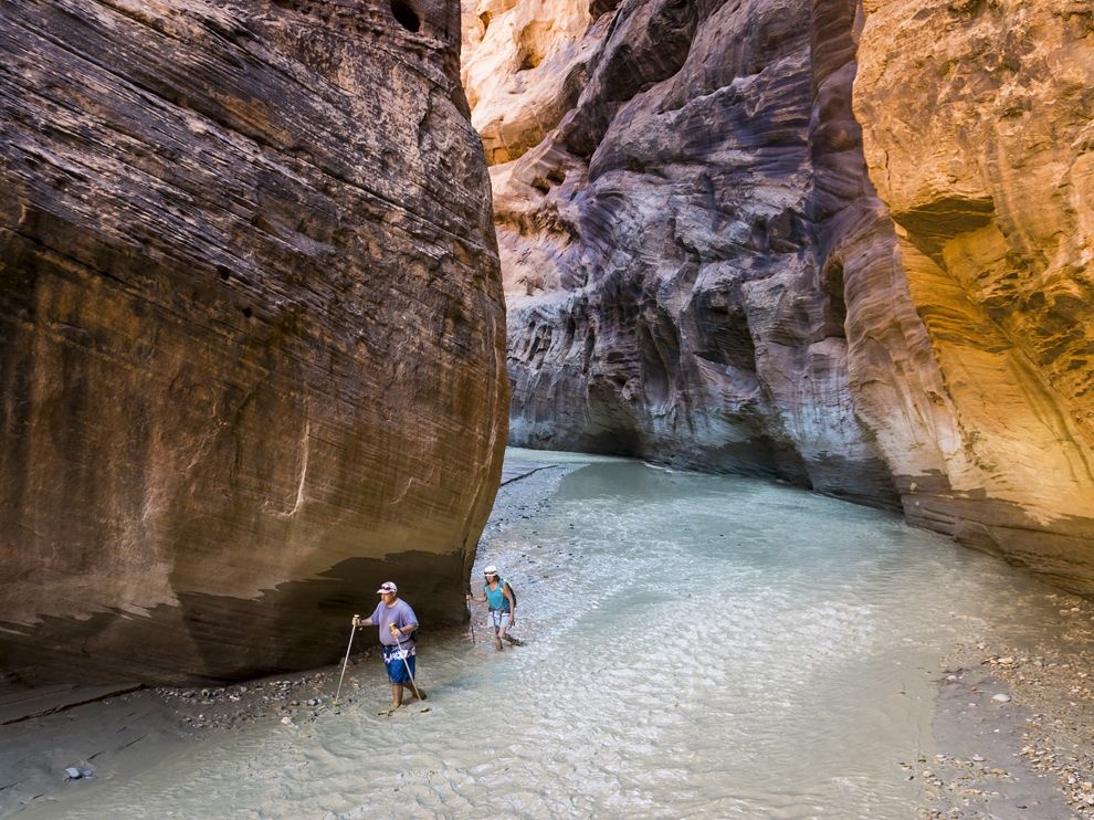 Sông Paria, Utah, Mỹ: Hai du khách lội qua khu vực nước nông của sông Paria. Những người mê hoạt động ngoài trời đổ về đây để khám phá hẻm núi Paria và những hành lang sa thạch uốn lượn quanh sông.